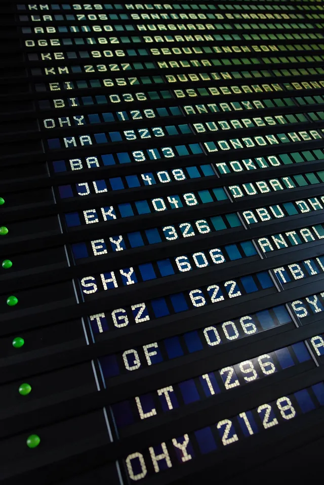 Airport split-flap departure board listing flights