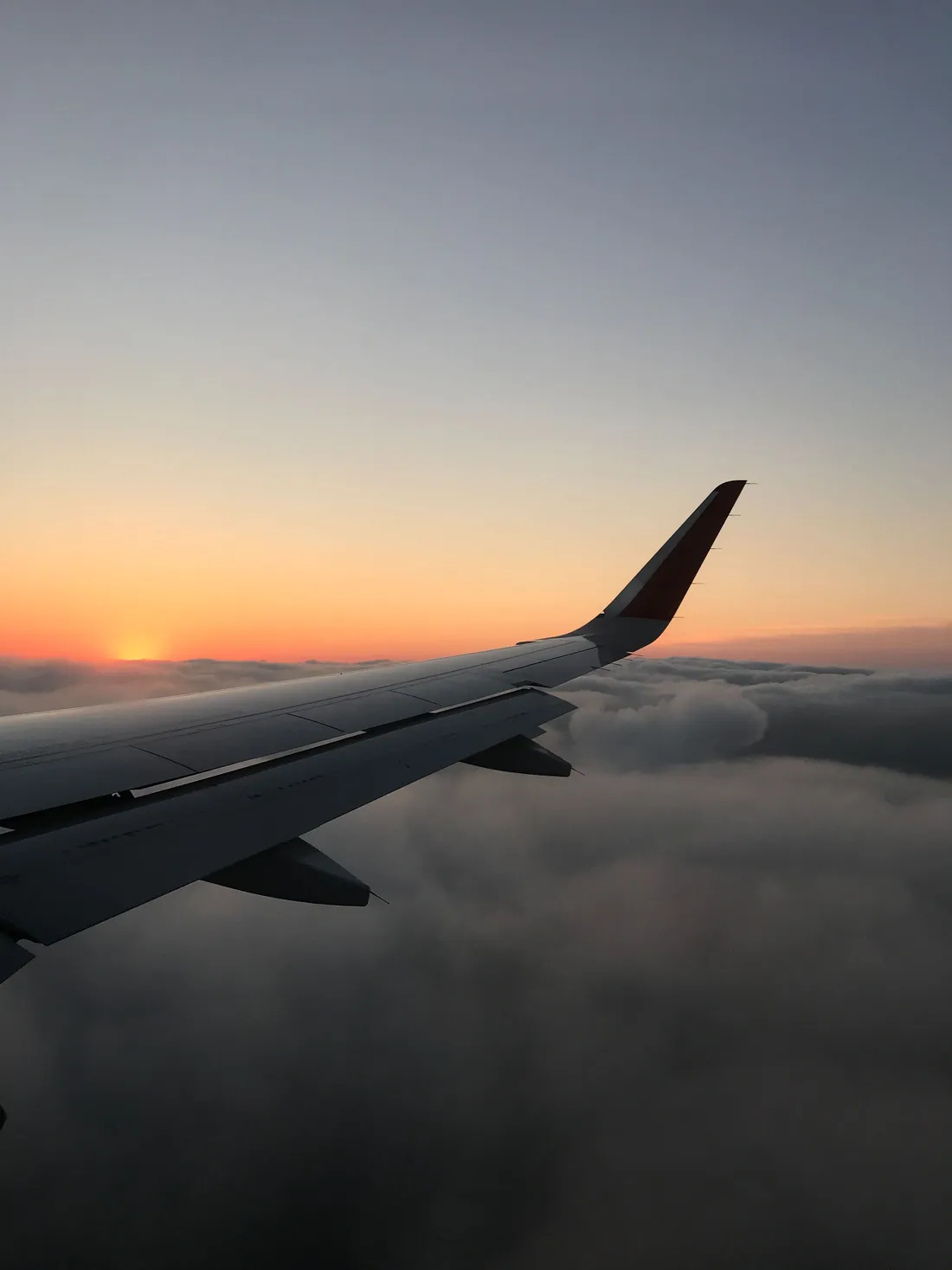Aircraft wing above the clouds at sunset